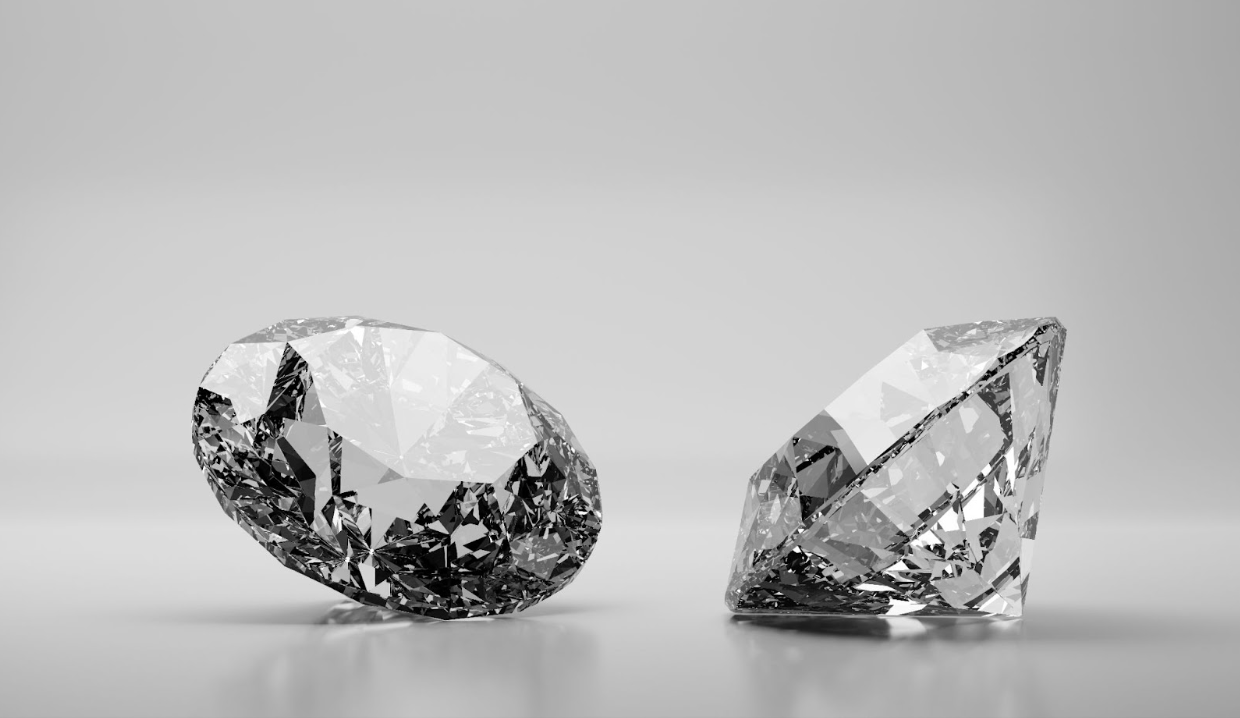 Two loose round brilliant-cut diamonds displayed on a reflective surface, showcasing their clarity and sparkle.