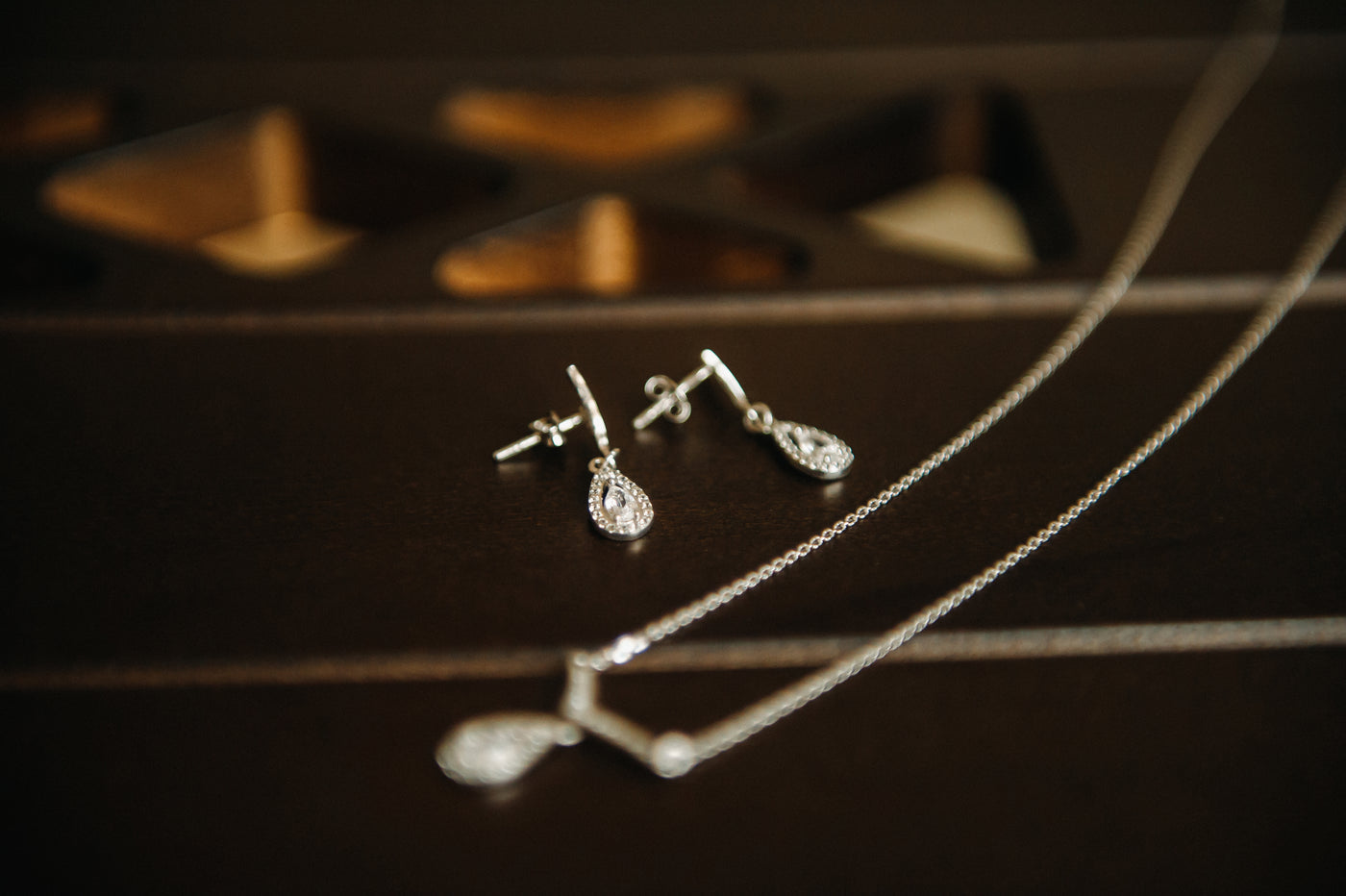 Gorgeous lab-grown diamond dangle earrings and a lab grown diamond pendant necklace on a black table top