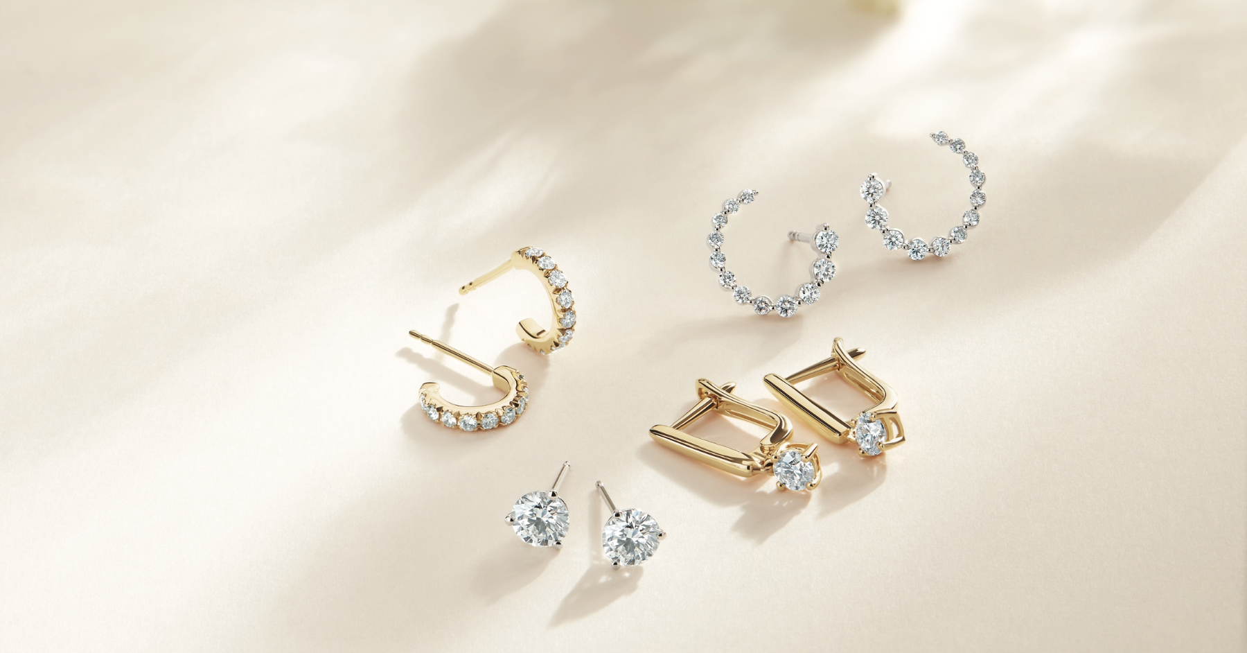 Lab-grown diamond stud earrings, necklace and ring displayed on an elegant white background