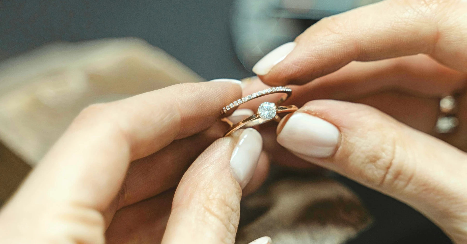 Women's hands holding a gold diamond engagement ring and gold diamond wedding band closeup