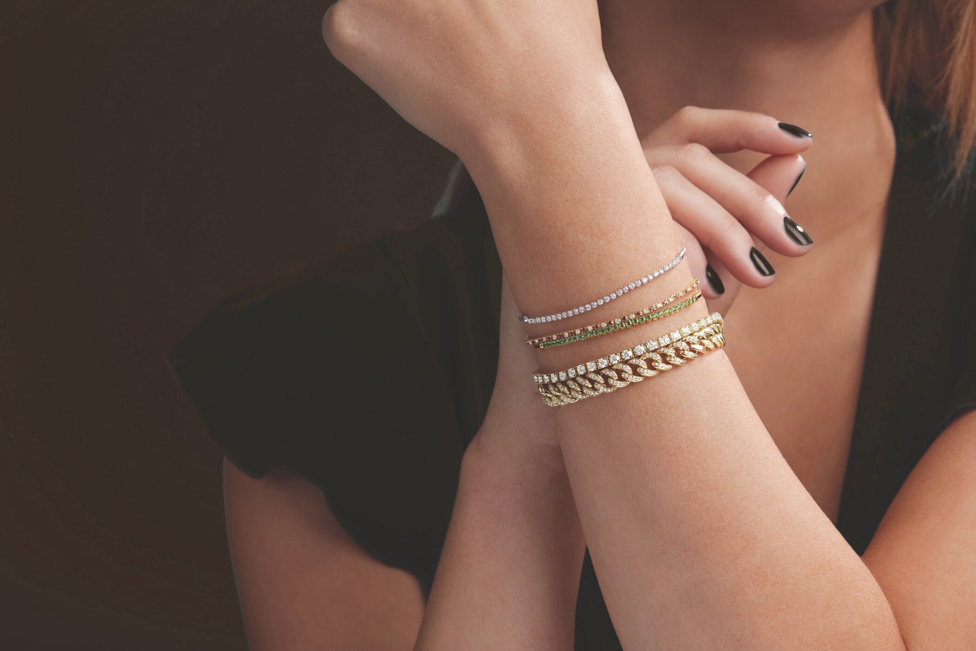 Close up photo of a women's wrist with a stack of different diamond bracelets