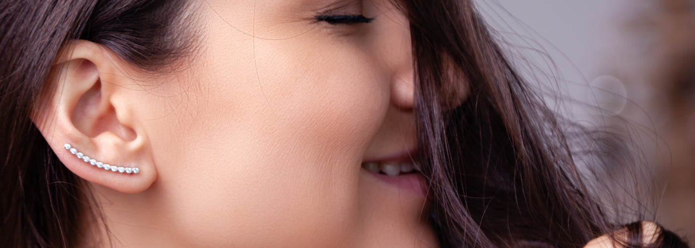A profile of a women's face with dark brown hair, showing her ear which features a lab-grown diamond climber earring