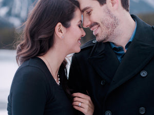 A happy couple hugging during an engagement photo shoot, showing off her lab grown diamond engagement ring on her hand.