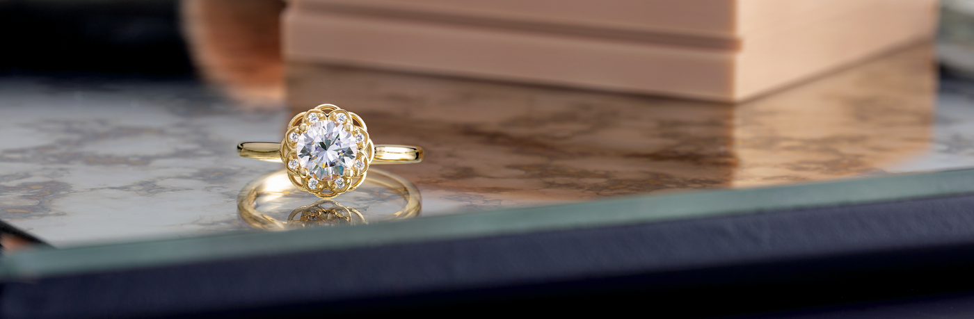 Beautiful lab-grown diamonds set in a stunning yellow gold setting and band, on top of a table facing diamond first.